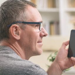 Man with a hearing aid uses his phone.