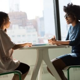 Two women having a conversation at a table.
