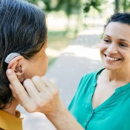 Woman with hearing aid having a conversation with her friend outside.