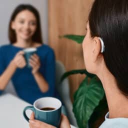 Woman with a hearing aid having coffee with a friend