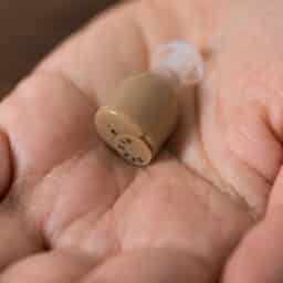 Hand holding an in-the-canal hearing aid