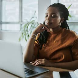 Well-dressed woman looking at a laptop on a table.