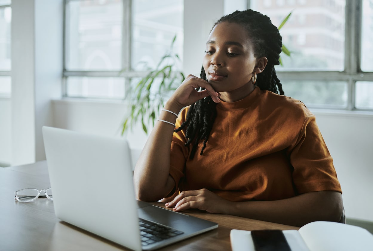 Well-dressed woman looking at a laptop on a table.