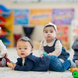 Four cute babies sitting on the floor looking curious