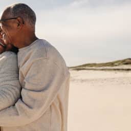 Happy older couple still deeply in love, embracing on a beach.