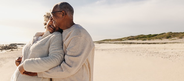 Happy older couple still deeply in love, embracing on a beach.